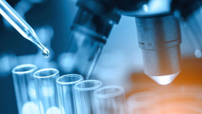 Pipette und Reagenzgläser vor einem Mikroskop